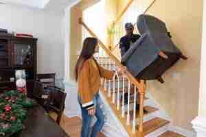 Trash and Stash staff moves furniture down stairs while customer looks om