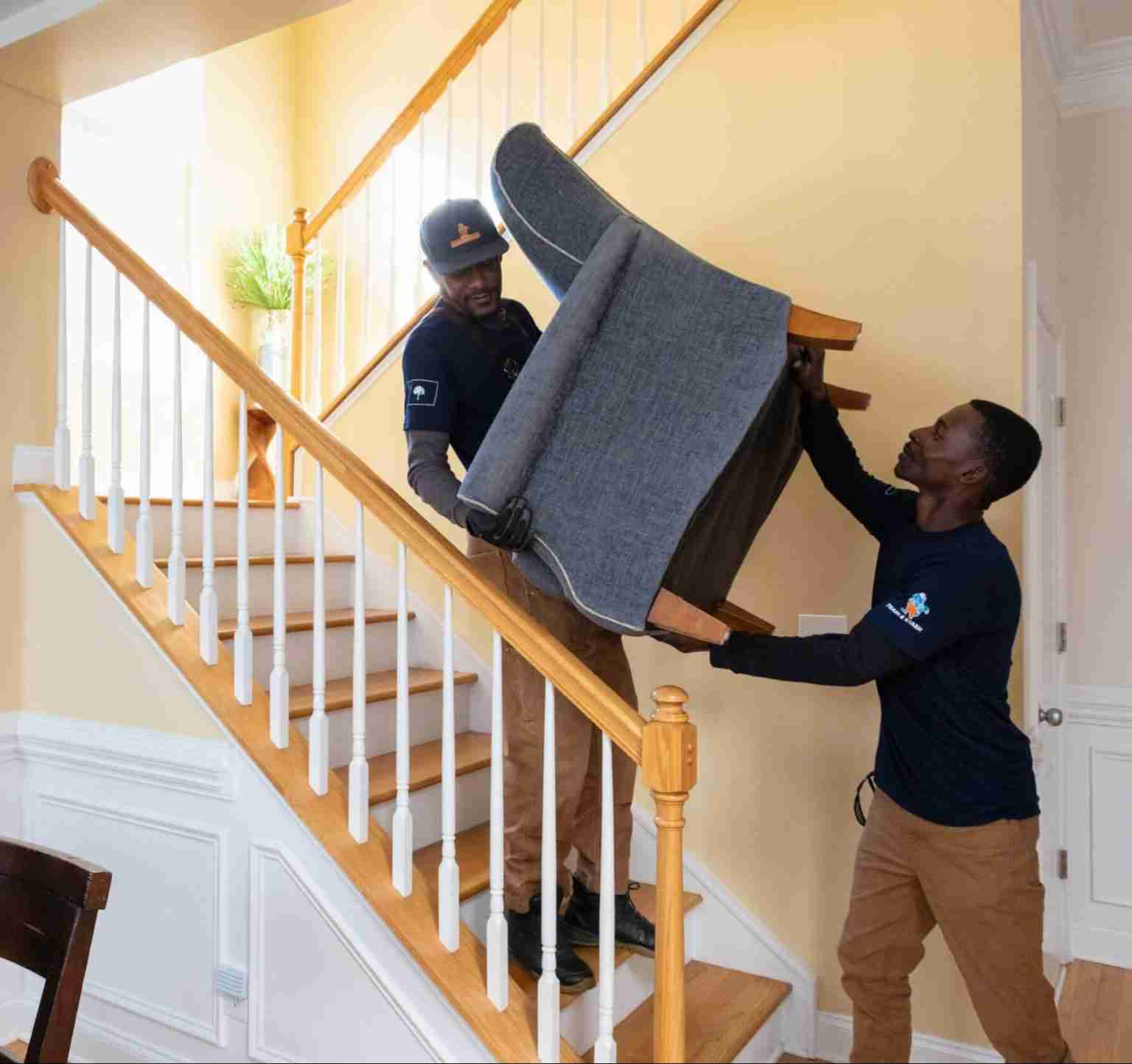 Trash and Stash crew moving a chair down stairs