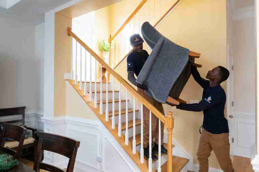 Trash and Stash crew carrying a chair downstairs