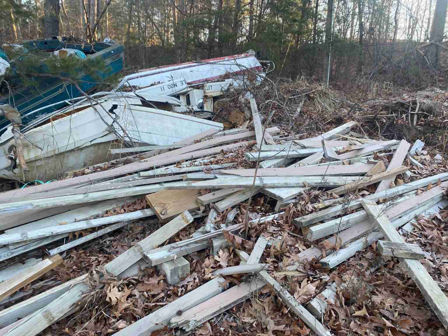 boats and decking material scattered in woods.