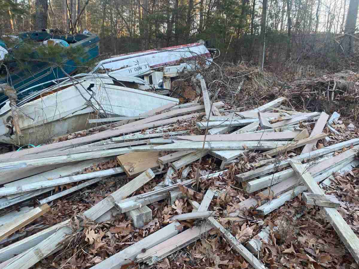 boats and decking material scattered in woods.