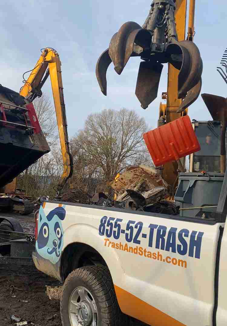 scrap yard claw removes metal from bed of truck